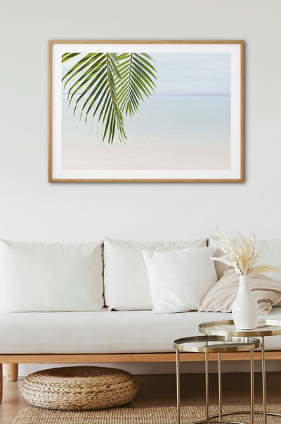 Framed Shoreline Oasis artwork on a wall above a white sofa.