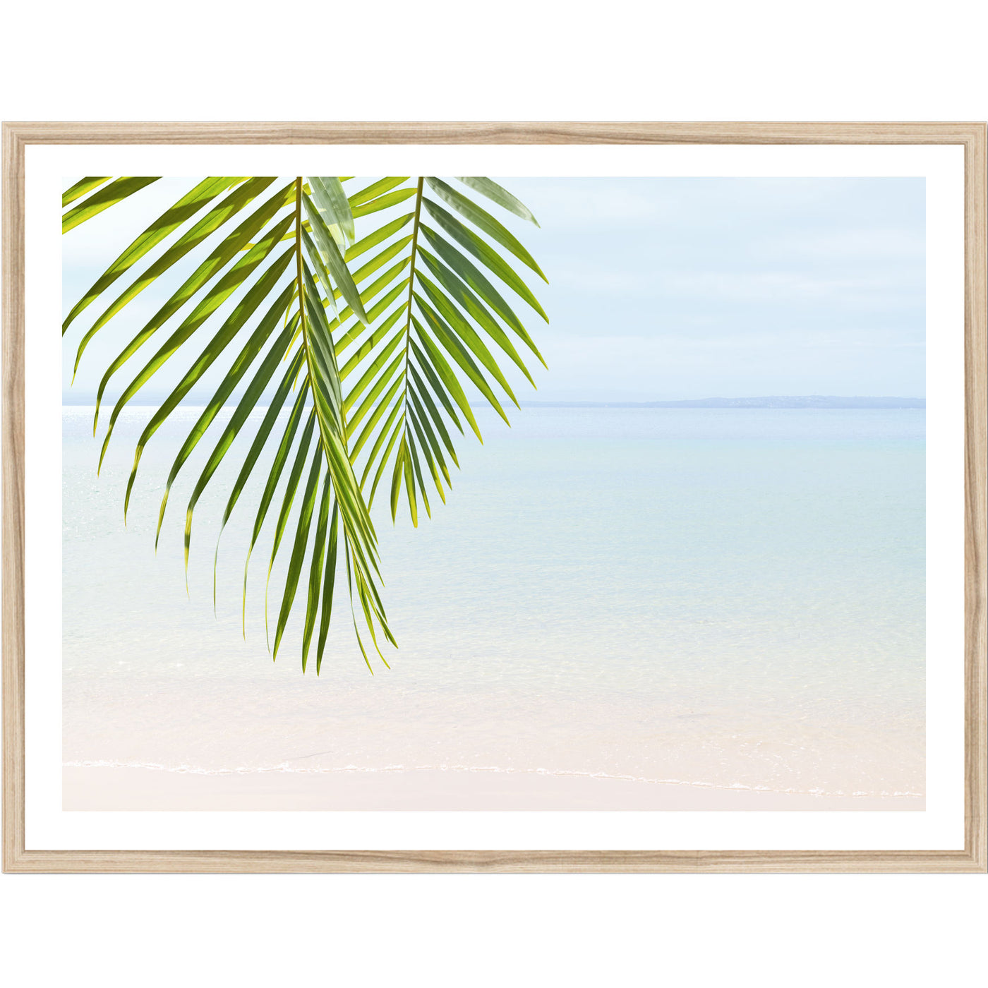 Framed artwork with a palm leaves against a tranquil beach background